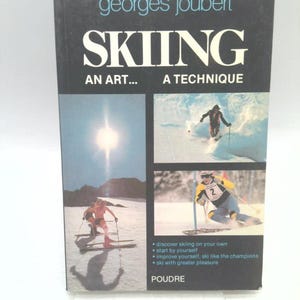 May include: A book titled "SKIING AN ART... A TECHNIQUE" by Georges Joubert. The cover is black with white text and images of skiers in action. The book also includes the text "discover skiing on your own" and "POUDRE".