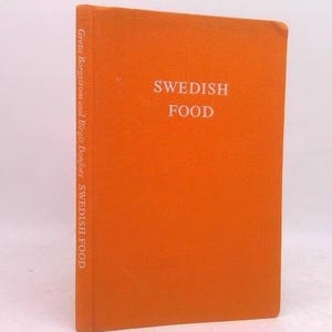 May include: An orange hardcover book titled "SWEDISH FOOD" in white lettering. The spine reads "Greta Borgstrom and Birgit Danfors SWEDISH FOOD" in white. The book is standing upright against a white background.