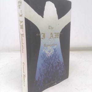 Puede incluir: Un libro titulado "The 'I AM' Revelation" de Clement Humbard. La portada presenta una silueta blanca sobre un fondo negro, con el título en letras doradas y una ilustración azul y morada.