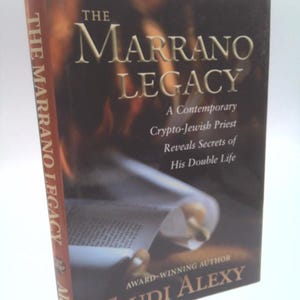 May include: A hardcover book titled The Marrano Legacy by Trudi Alexy. The cover features a dark, fiery background with a scroll in the foreground. The text reads: The Marrano Legacy, A Contemporary Crypto-Jewish Priest Reveals Secrets of His Double Life.