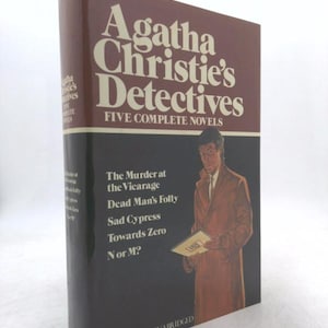 May include: A hardcover book titled "Agatha Christie's Detectives: Five Complete Novels." The cover features a brown and black design with white text. The book's spine and cover display the title and a list of novels.