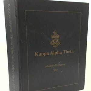May include: A black hardcover book titled "Kappa Alpha Theta Alumnae Directory 1993." The cover features the sorority's crest and the title in gold lettering. The book is slightly angled, showing the spine with the title.