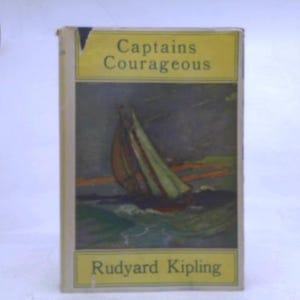 May include: A hardcover book titled Captains Courageous by Rudyard Kipling. The cover features a yellow rectangular border at the top and bottom with black text. The central illustration depicts a sailboat on dark, wavy water under a dim sky.