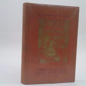 May include: A vintage, hardcover book with a reddish-brown cover. The cover features a gold illustration and text. The book's title and author are visible, along with additional text at the bottom. The book is in good condition.