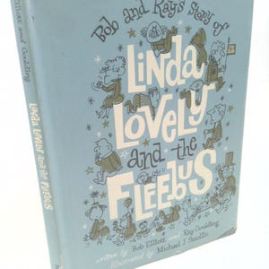 May include: Vintage book titled "Bob and Ray's Story of Linda Lovely and the Fleebus." The cover is light blue with illustrations of cartoon characters and text. The book's spine reads "Linda Lovely and the Fleebus."