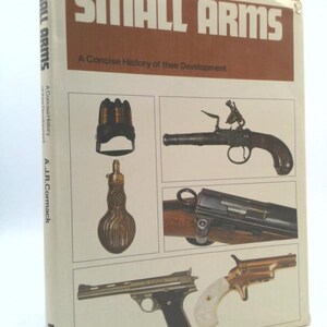 May include: A book titled "SMALL ARMS" with the subtitle "A Concise History of their Development." The cover features illustrations of various firearms, including a pistol and a rifle. The spine reads "SMALL ARMS" and "Profile."