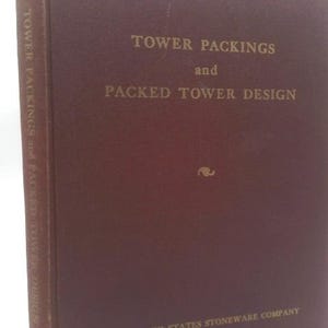 May include: A maroon-colored book titled "Tower Packings and Packed Tower Design." The title is in gold lettering. The book's spine also has the title printed vertically. The publisher is the United States Stoneware Company.