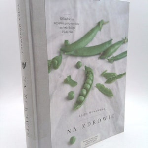 May include: A white book cover with a green pea pod and peas on a white background. The title of the book is "Na Zdrowie" by Eliza Morawska.