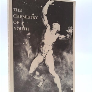 May include: A book cover with a black and white image of a nude male figure reaching up towards a starry sky. The title "THE CHEMISTRY OF YOUTH" is printed in white letters on the cover.