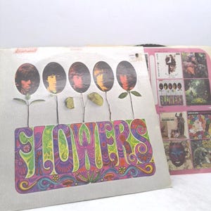 May include: Vintage vinyl record album cover titled "Flowers." The cover features five oval portraits of band members as flower heads, with the word "FLOWERS" in colorful psychedelic lettering. A second album cover is visible.