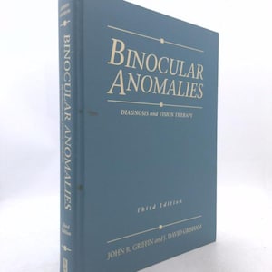 May include: A blue hardcover textbook titled Binocular Anomalies: Diagnosis and Vision Therapy, Third Edition, by John R. Griffin and J. David Grisham. The cover features gold lettering and horizontal lines, with the title repeated on the spine.