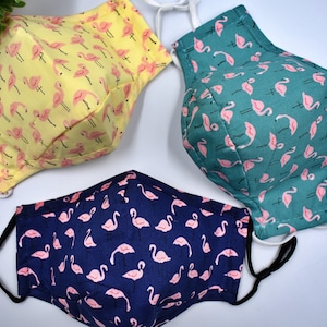 May include: Three reusable face masks with a flamingo print. The masks are yellow, teal, and navy blue.