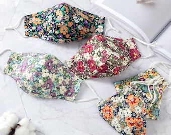 May include: Four reusable face masks with floral patterns. The masks are made of cotton fabric and have adjustable ear loops. The masks are in a variety of colors, including pink, green, blue, and orange.