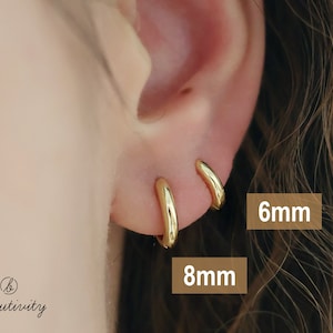 May include: Close-up of a person's ear with two gold hoop earrings. The earrings are 6mm and 8mm in diameter.