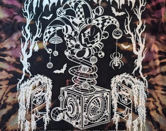May include: A black and purple tie-dye t-shirt featuring a white graphic of a jester jack-in-the-box with disco balls, bats, and trees. The text reads HULAWEEN, OCT. 22-25 2026, LIVE OAK, FL, and lists numerous musical artist names below.