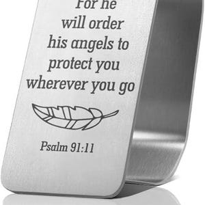 May include: A brushed silver metal bookmark with a curved U-shape. The front is engraved with the text 'For he will order his angels to protect you wherever you go', a line drawing of a single feather, and the reference 'Psalm 91:11' below it.