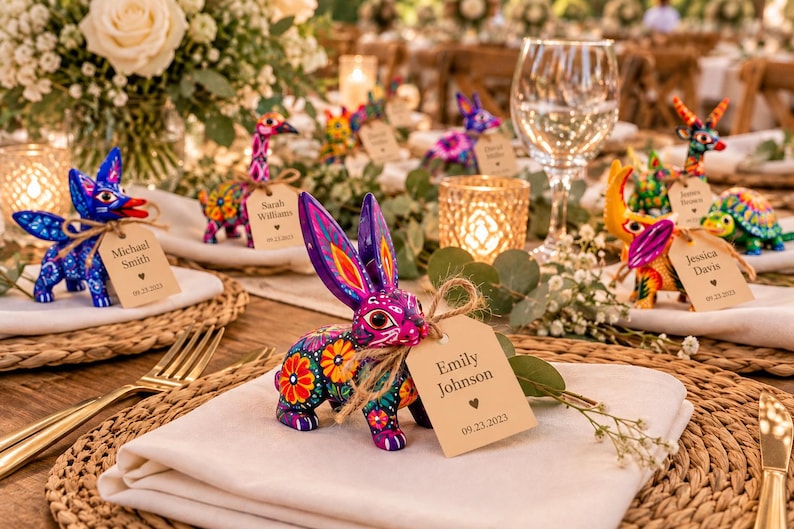 May include: A hand-painted purple rabbit figurine with intricate floral patterns in orange, yellow, and green. A tan rectangular paper tag tied with twine hangs from its neck, displaying the text Emily Johnson and 09.23.2023.