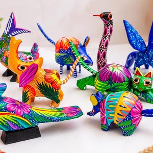 May include: A collection of small, hand-painted wooden animal figurines featuring vibrant, multi-colored patterns. The group includes a bird, elephant, zebra, cat, and other creatures, all decorated with intricate floral and geometric designs.