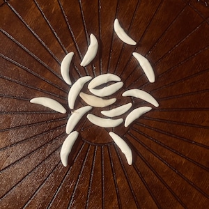 May include: A wooden board with a circular design and white crescent shapes arranged in a sunburst pattern.