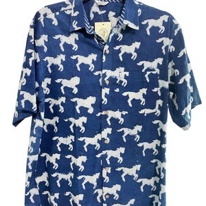 May include: A blue short-sleeved button-down shirt with a white horse print all over. The shirt has a white button-up collar and a pocket on the left side.