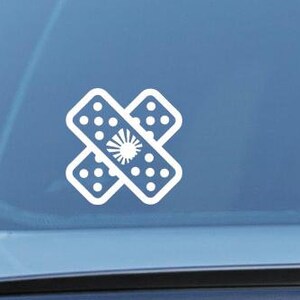 May include: A white vinyl sticker of a band-aid with a white star in the center, applied to the back window of a car.