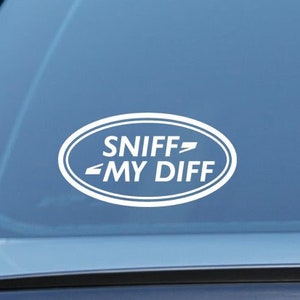 Può includere: Adesivo ovale bianco su un finestrino di un'auto blu che dice "SNIFF MY DIFF".