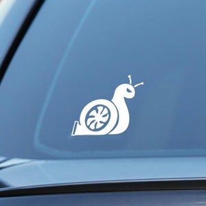 Op de afbeelding: Een witte vinyl sticker van een slak met een turbolader als schelp op de achterruit van een auto.
