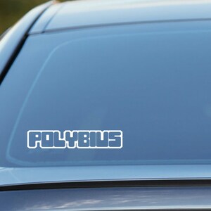 May include: A white vinyl sticker with the word "POLYBIUS" in a retro, blocky font. The sticker is applied to the rear window of a silver car.
