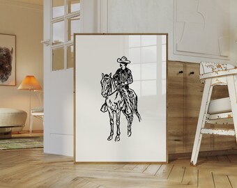 Può includere: Stampa in bianco e nero di arte lineare di un cowboy a cavallo. La stampa è incorniciata e appesa a una parete in una stanza con pavimento in legno.