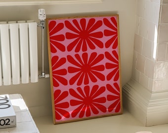 May include: A framed print with a pink background and a repeating pattern of red stylized flowers.