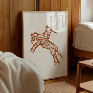 May include: A brown silhouette of a cowboy riding a bucking horse. The image is on a white background.