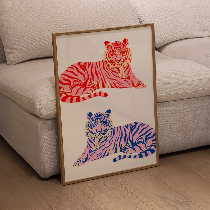 May include: A framed print featuring two stylised tigers, one in pink and blue and the other in red and blue, with a white background.