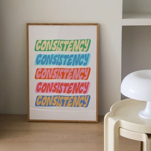 May include: A framed print with the word "CONSISTENCY" repeated five times in a colorful, layered design. Each word is a different color: green, blue, light blue, pink, and orange.