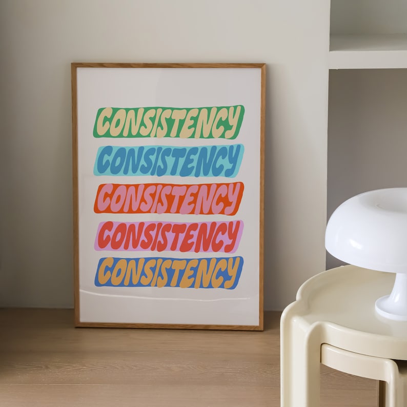 May include: A framed print with the word "CONSISTENCY" repeated five times in a colorful, layered design. Each word is a different color: green, blue, light blue, pink, and orange.