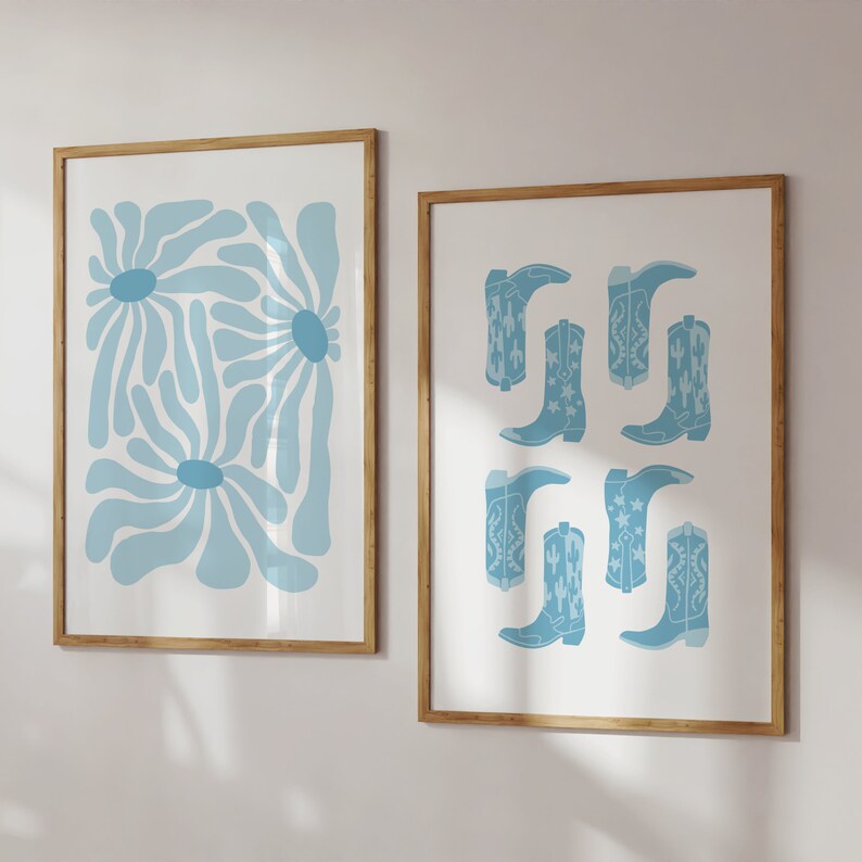 May include: Two framed prints with a light blue color scheme. The print on the left features a stylized abstract design of blue flowers. The print on the right features a pattern of blue cowboy boots with white stars.
