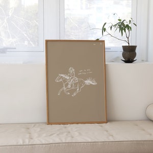 Pu&ograve; includere: Una stampa incorniciata con uno sfondo beige che presenta un disegno a linea di una persona a cavallo. Il testo "Dare to seek and feel it all" &egrave; scritto sotto l'immagine.