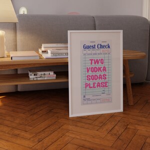 K&ouml;nnte beinhalten: Ein wei&szlig; gerahmter Druck eines alten Gastchecks mit dem Text "TWO VODKA SODAS PLEASE" in rosa Schrift. Die Checknummer lautet 302701.