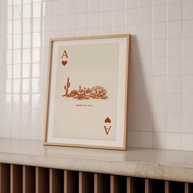 May include: A framed print of an ace of hearts playing card with a desert landscape illustration. The card is printed in orange on a cream background. The text "Made in the U.S.A." is printed below the illustration.