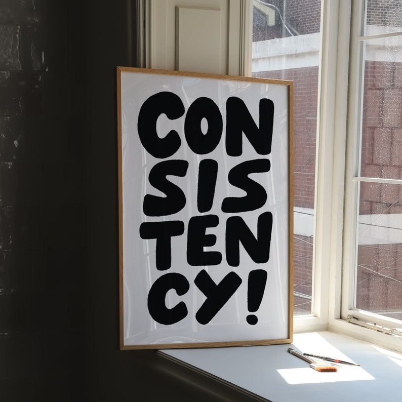 May include: A framed print with the word "CONSISTENCY" written in large, black, bold letters on a white background.
