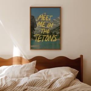 May include: A framed print with a mountain landscape and the text "Meet me in the Tetons" in yellow lettering.