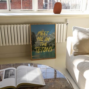 May include: A framed print with a mountain scene and the text "Meet me in the Tetons" in gold lettering.