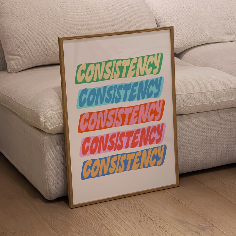 May include: A framed print with the word "CONSISTENCY" repeated five times in a colorful, retro font. Each word is a different color: green, blue, red, pink, and yellow.