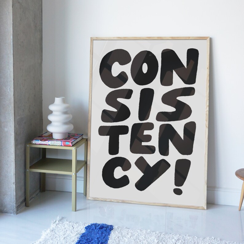 May include: A framed print with the word "CONSISTENCY" in large, black, stylized letters on a white background.