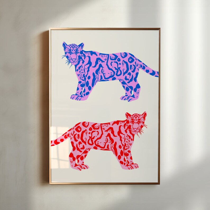 Op de afbeelding: Een ingelijst drukwerk met twee gestileerde illustraties van luipaarden. De bovenste luipaard is roze met blauwe vlekken en de onderste luipaard is roze met rode vlekken.
