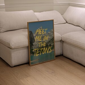 May include: A framed print with a mountain scene and the text "Meet me in the Tetons" in yellow lettering.