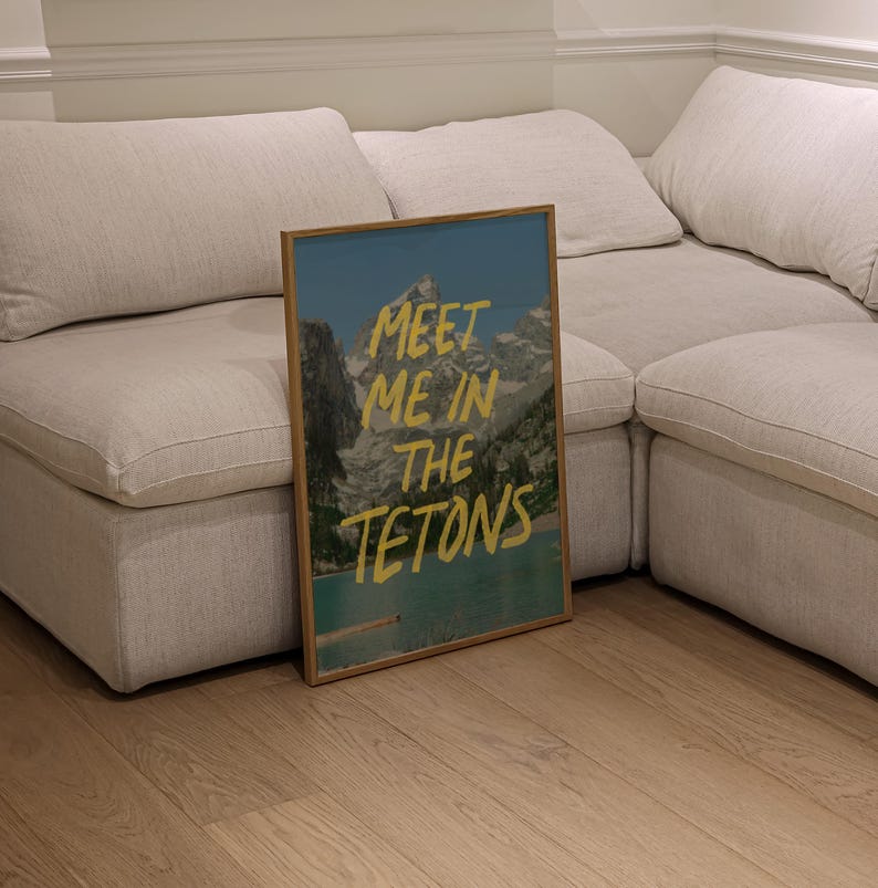 May include: A framed print with a mountain scene and the text "Meet me in the Tetons" in yellow lettering.