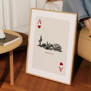 Op de afbeelding: Een ingelijst afdruk van een aas harten speelkaart met een woestijnlandschap illustratie en de tekst "Made in the U.S.A."