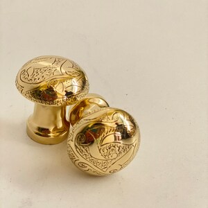 Peut inclure: Deux boutons de porte dorés avec des motifs floraux complexes.