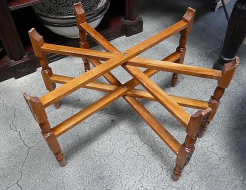 May include: A wooden table base with a starburst design. The base is made of light brown wood and has a rustic look.