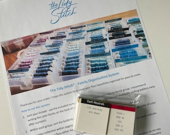 May include: A white sheet of paper with instructions on how to organize embroidery floss by color family. The paper includes the text "The Tidy Stitch - Family Organization System". There are also color-coded cards with floss numbers and names.